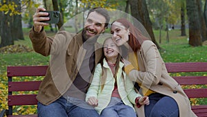 Happy Caucasian couple parents mother father little cute daughter child kid girl making selfie photo with smartphone