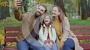 Happy Caucasian couple parents mother father little cute daughter child kid girl making selfie photo with smartphone