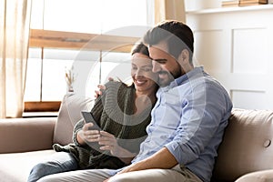 Happy Caucasian couple use cellphone at home together