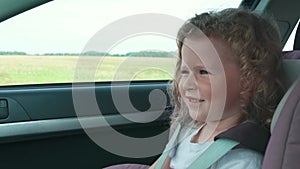 Happy caucasian daughter having fun with her family while traveling by car in summer. Cute four year old girl in a child