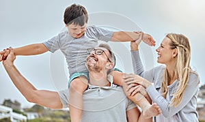 Happy caucasian family bonding together at the beach. Excited little boy sitting on his fathers shoulders and holding