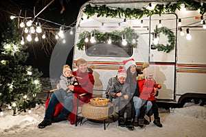 Happy Caucasian family celebrating Christmas outdoors. Parents and three sons travel in a camper.