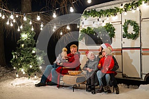 Happy Caucasian family celebrating Christmas outdoors. Parents and three sons travel in a camper.