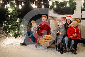 Happy Caucasian family celebrating Christmas outdoors. Parents and three sons travel in a camper.