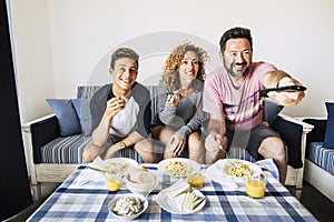 Happy caucasian family cheerful people have lunch together at home watching tv and having fun - young teenager son and adult