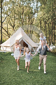 Happy Caucasian family, father mother and two little daughters, having fun outdoors in park or camping, enjoying time