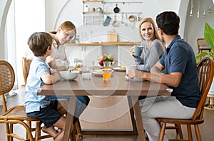 Happy Caucasian family having breakfast together at table . Beautiful kind family talking while eating together in the modern