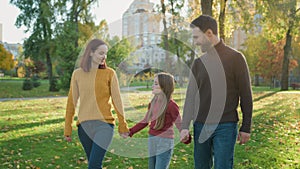 Happy Caucasian family holding hands walking in park talking parents child talk speaking conversation walk go in city