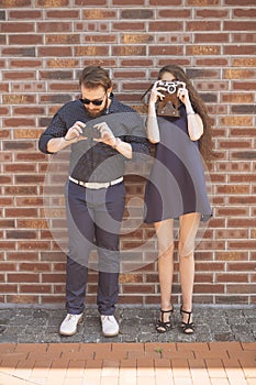 Happy caucasian family of mother and father on a walk in european city, dressed in casual outfit, holding photocameras. Summer da