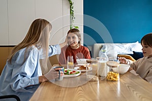 Happy caucasian family mother and two kids talking and smiling while having breakfast together