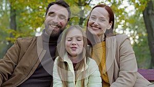 Happy Caucasian family parents mother father daughter child girl kid daughter at autumn park outdoors smiling looking at