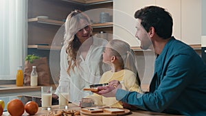 Happy Caucasian family preparing breakfast together talking at home kitchen mother hold glasses with milk little