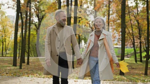 Happy Caucasian family retired married couple 60s old mature woman man going walking in city park autumn nature carefree