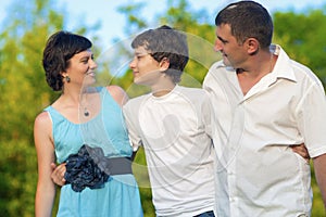 Happy Caucasian Family of Three Spending Time Together. Walking Embraced in Park.