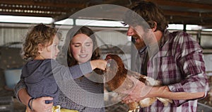 Happy caucasian family working on farm, holding chicken