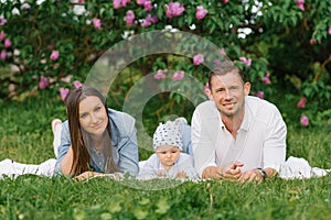 Happy Caucasian family with a young son relax in the park in spring or summer, lying on a blanket