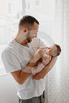 Happy Caucasian father holding newborn baby. Male man parent rocking talking to child daughter son in his hands. Authentic