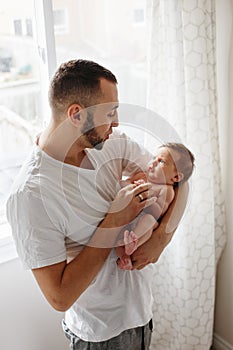 Happy Caucasian father holding newborn baby. Male man parent rocking talking to child daughter son on his hands. Authentic