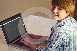 Happy caucasian female programmer siting at desk at laptop with coding on screen