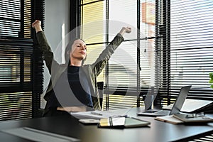 Happy caucasian female worker stretching arms, relaxing on comfortable office chair in modern office workplace