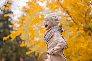 Happy caucasian girl in a beige coat and beret walks in the park in autumn.