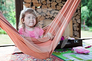 Happy Caucasian girl swinging on hammock in wooden veranda