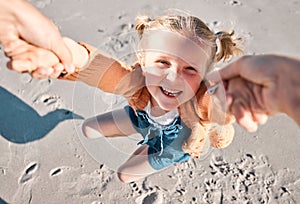 Happy caucasian girl swinging and spinning in circles by the arms at the beach shore with her father. Face of cute