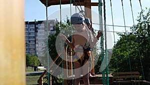 Happy Caucasian girls in an adventure park in protective gear on a summer day. Rope park. nature walks. Physical health