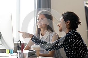 Happy caucasian intern listening to indian mentor explaining com photo