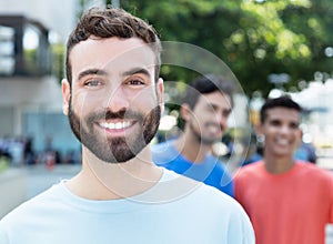 Happy caucasian man with beard with two friends in the city