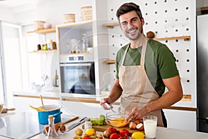 Happy caucasian man cooking in kitchen at home, smiling.