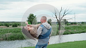 Happy Caucasian man holding brunette woman in his arms, spinning her around on a summer day. Couple, date, love and