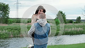 Happy Caucasian man holding brunette woman in his arms, spinning her around on a summer day. Couple, date, love and