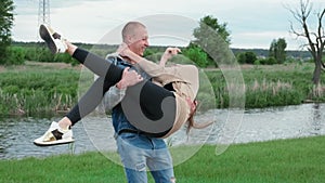 Happy Caucasian man holding brunette woman in his arms, spinning her around on a summer day. Couple, date, love and