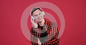 Happy caucasian man listening music on red background