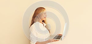 Happy caucasian middle-aged woman working with laptop at home