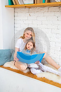 Happy caucasian mom with her daughter reading a book and smiling