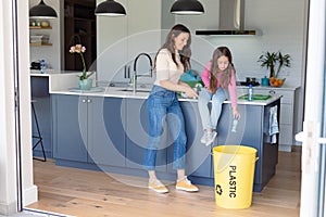 Happy caucasian mother and daughter segregating rubbish