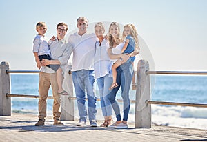 Happy caucasian multi-generation family standing together on seaside promenade on a sunny day. Two little children