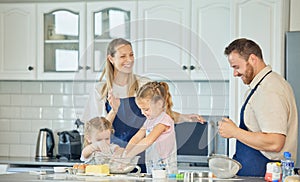 Happy caucasian parents and their little daughters baking together in a kitchen at home. Mother and father teaching