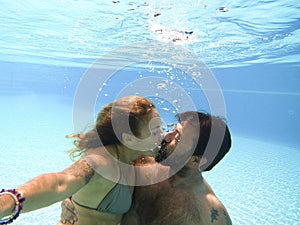Happy caucasian people couple have fun and enjoy the swimming activity at the pool - concept of holiday summer vacation in resort