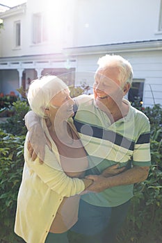 Happy caucasian senior couple embracing and looking at each other in sunny garden