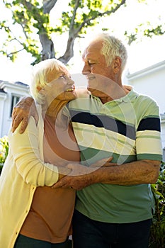 Happy caucasian senior couple embracing and looking at each other in sunny garden, copy space