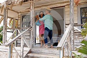 Happy caucasian senior couple wife dancing cheerfully on balcony outside wooden cottage