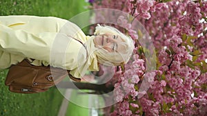 Happy Caucasian senior woman looking at camera in the park for outdoor walk or mindset for wellness city park. Beautiful