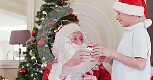 Happy caucasian siblings with santa claus giving presents at christmas