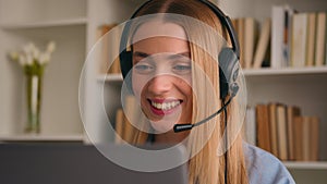 Happy Caucasian smiling woman in headset talking conference call video chat speak at computer laptop at home office job