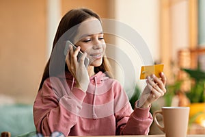 Happy caucasian teen girl in casual outfit making order, talking on cellphone and holding credit card,copy space