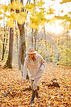 Happy caucasian woman collecting yellow leaves in the forest