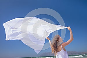 Happy Caucasian woman holding scarf at beach